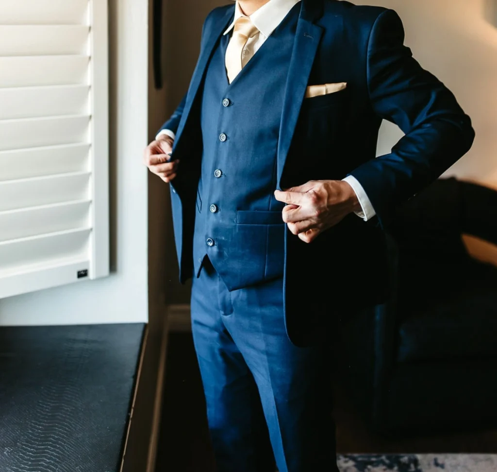 Groom Wearing A Navy Blue Three-Piece Suit With A Gold Tie And Pocket Square, Showing A Modern Wedding Style In Phoenix.