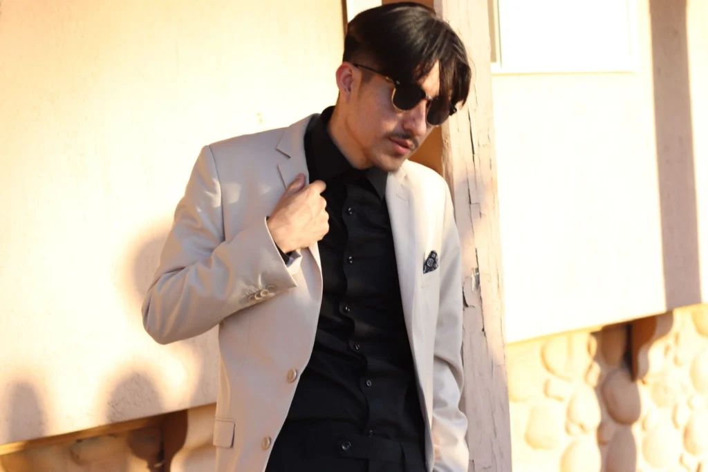 Man Adjusting His Beige Suit Jacket While Wearing A Black Shirt In Phoenix, Showing A Modern Suit Combination.