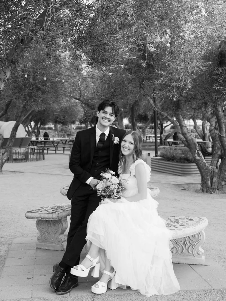 Groom In Tailored Black Three-Piece Suit Sitting With Bride At Outdoor Phoenix Wedding Venue, Comfortable In Any Season